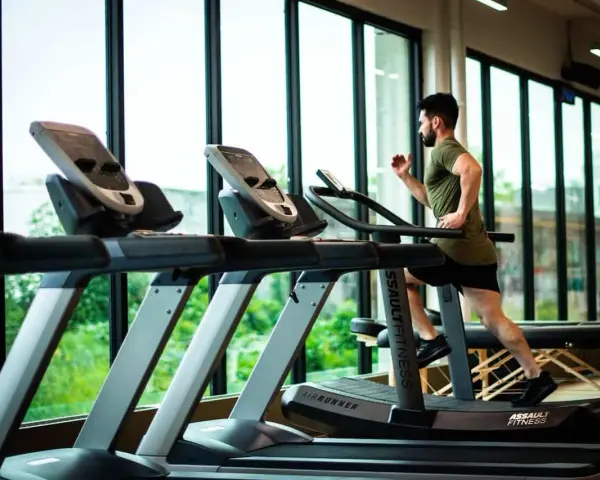 Hombre corriendo en cinta. ¿Qué es mejor bici estática o cinta de correr? La cinta ofrece un entrenamiento más completo.