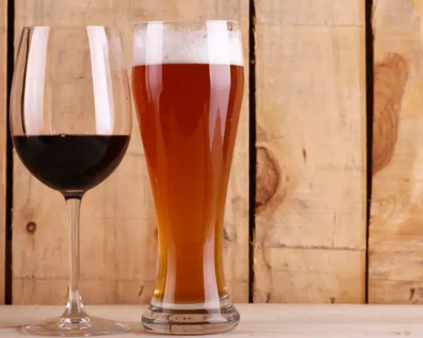 Copa de vino tinto y vaso de cerveza dorada con espuma. ¿Qué engorda más la cerveza o el vino? La respuesta está en las calorías.