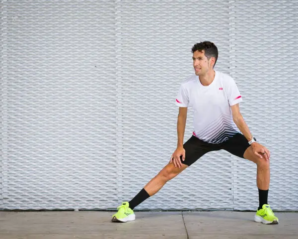 Corredor realiza estiramientos antes de correr, preparándose para su entrenamiento.