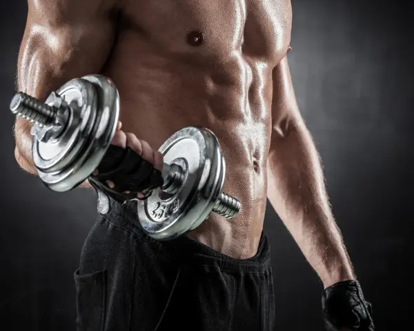 Hombre sudoroso entrenando bíceps con mancuerna. Descubre cuántas repeticiones hacer para ganar masa muscular y optimizar tu entrenamiento.