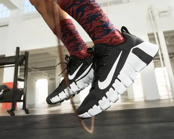 Pies con zapatillas Nike negras y calcetines rojos saltando la cuerda. La longitud de la cuerda de saltar es perfecta para el entrenamiento.
