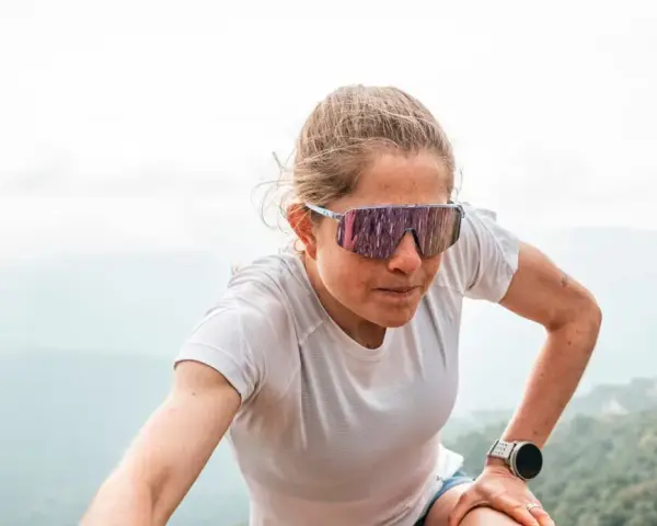 Mujer con gafas de correr, concentrada en su ascenso por la montaña.