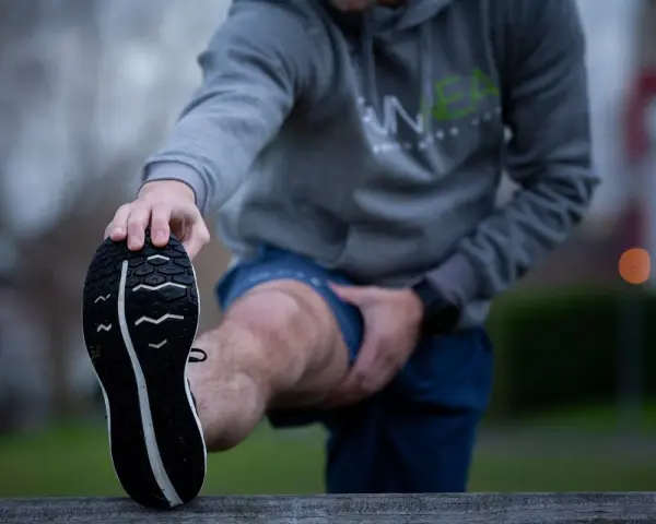 Hombre estirando la pierna antes de correr con agujetas.