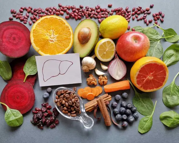 Una variedad de alimentos buenos para el hígado: remolacha, naranja, aguacate, limón, manzana, pomelo, espinacas, arándanos, café, canela, zanahoria, ajo, cebolla y nueces.