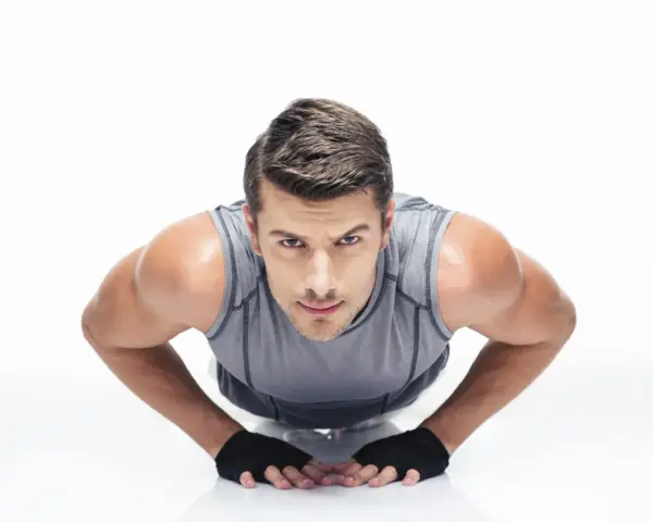 Hombre concentrado haciendo diamond push ups, con guantes negros y camiseta gris.