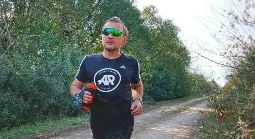 Hombre corriendo en un camino rural, con un bidón de agua en la mano. El antes y después de su entrenamiento.
