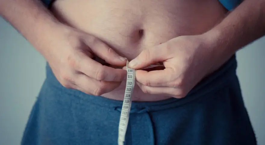 Man measuring waist with tape. A step towards understanding como activar la autofagia for better health.