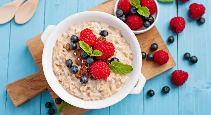 Un tazón de avena con frambuesas, arándanos y pasas. ¡Cuidado! La avena engorda si no se consume con moderación.