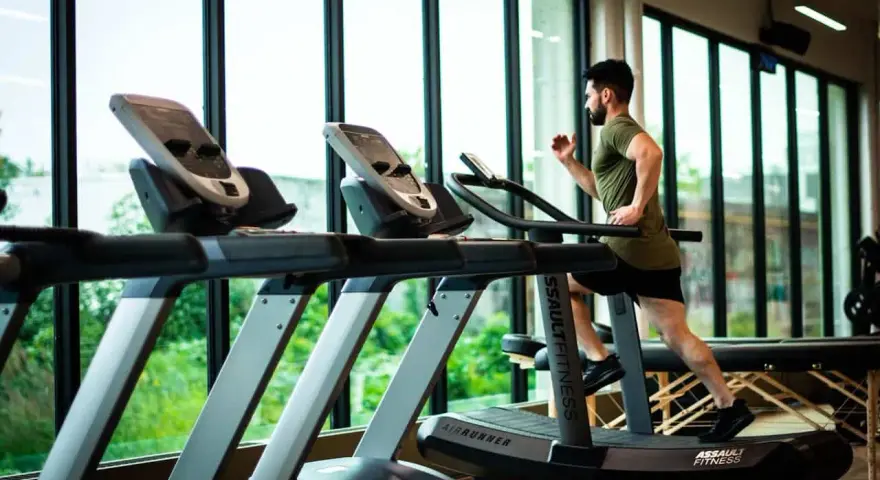 Hombre corriendo en cinta. ¿Qué es mejor bici estática o cinta de correr? La cinta ofrece un entrenamiento más completo.