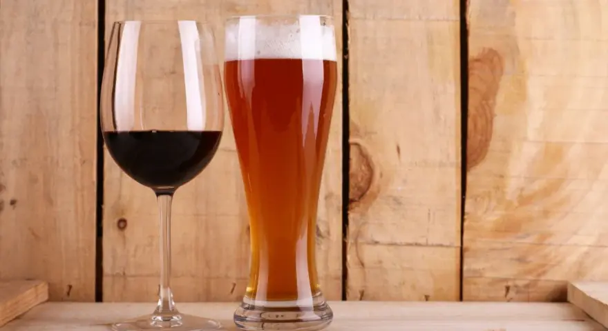 Copa de vino tinto y vaso de cerveza dorada con espuma. ¿Qué engorda más la cerveza o el vino? La respuesta está en las calorías.