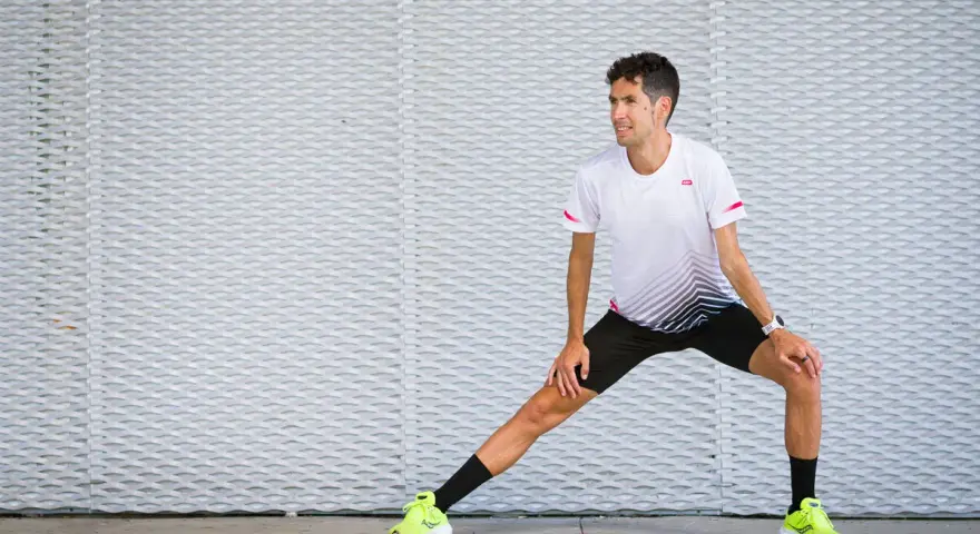Corredor realiza estiramientos antes de correr, preparándose para su entrenamiento.