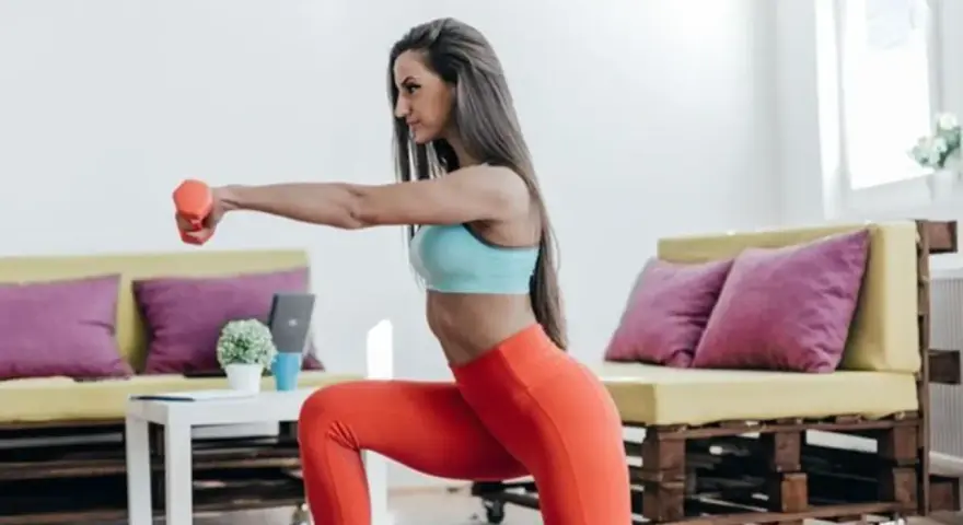 Mujer haciendo ejercicio en casa con mancuernas, a pesar de la posible exposición al frío, se mantiene activa.