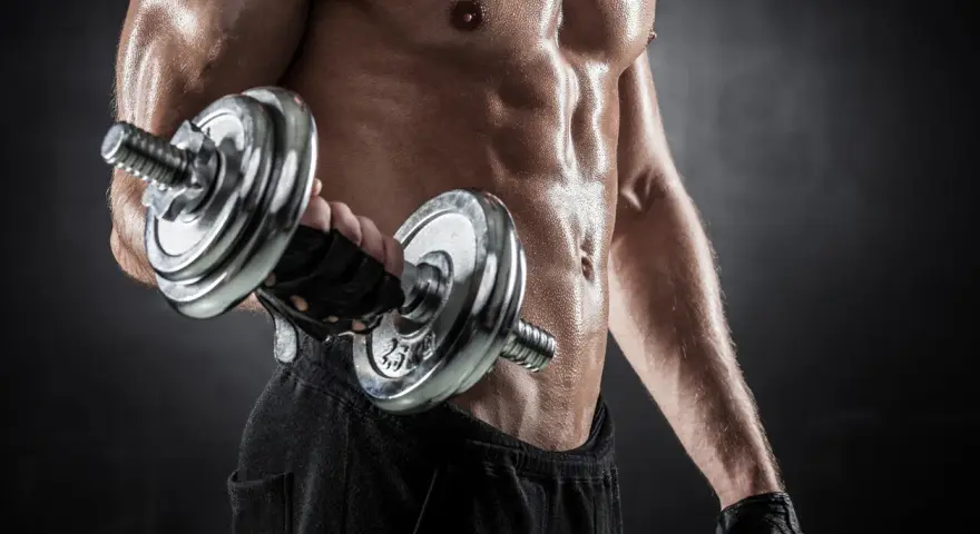 Hombre sudoroso entrenando bíceps con mancuerna. Descubre cuántas repeticiones hacer para ganar masa muscular y optimizar tu entrenamiento.