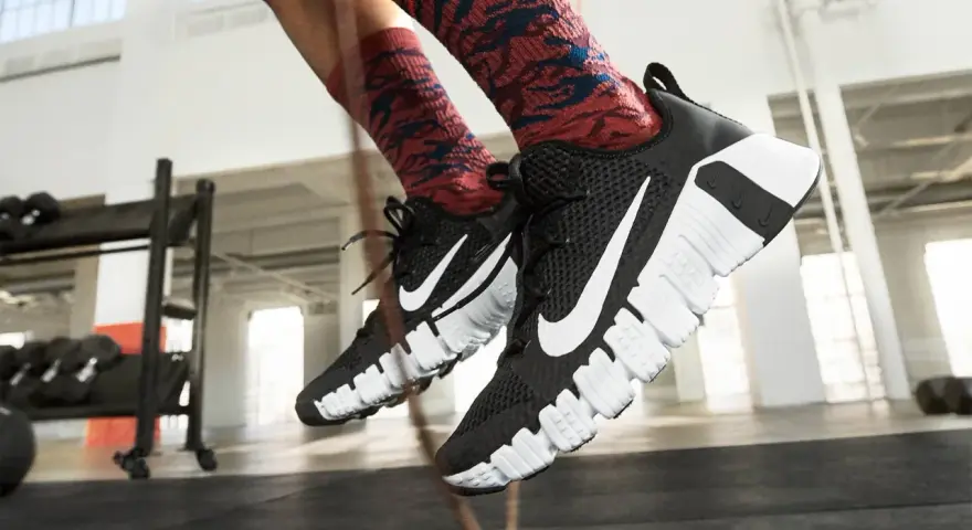 Pies con zapatillas Nike negras y calcetines rojos saltando la cuerda. La longitud de la cuerda de saltar es perfecta para el entrenamiento.