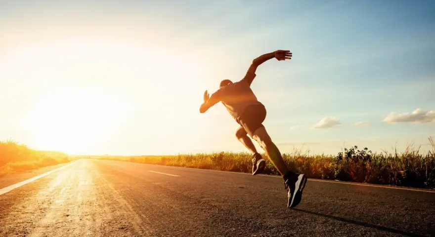 Corredor en una carretera al atardecer, experimentando lo que es un tempo run: un esfuerzo sostenido y desafiante.