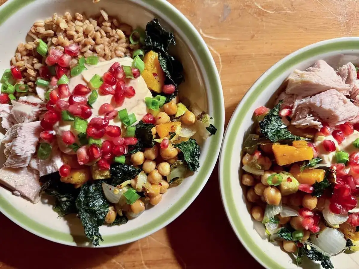 Dos bowls llenos de farro, garbanzos, pavo, calabaza, col rizada y granada. &iexcl;Una comida completa y deliciosa!
