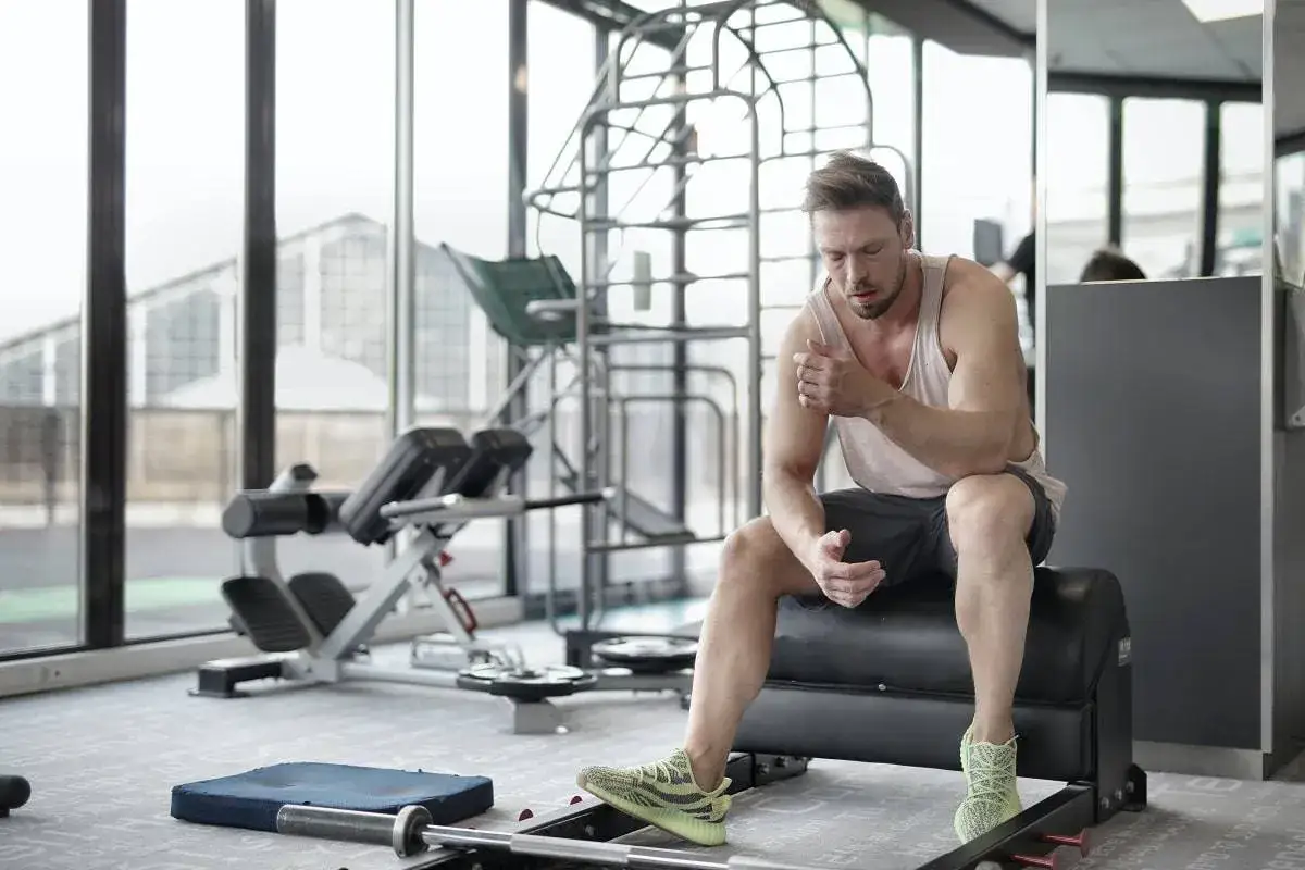 Hombre en el gimnasio, reflexionando sobre cuanto descansar entre series.