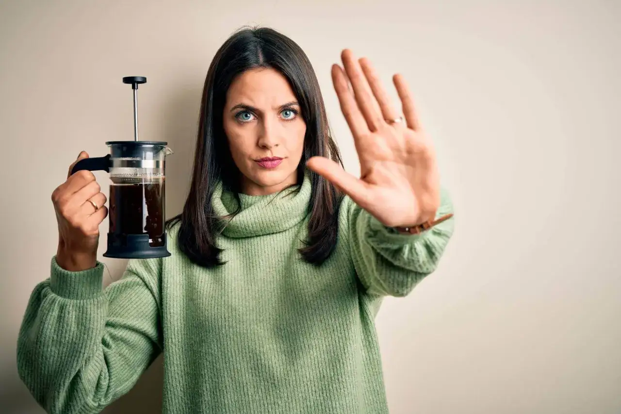 Mujer con cafetera de &eacute;mbolo y mano extendida, diciendo 