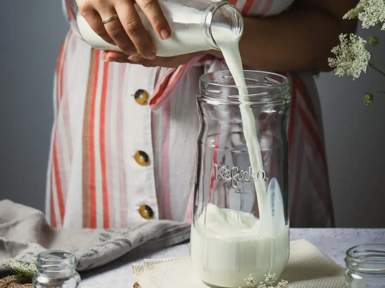 Manos vierten leche en un tarro de cristal con la palabra