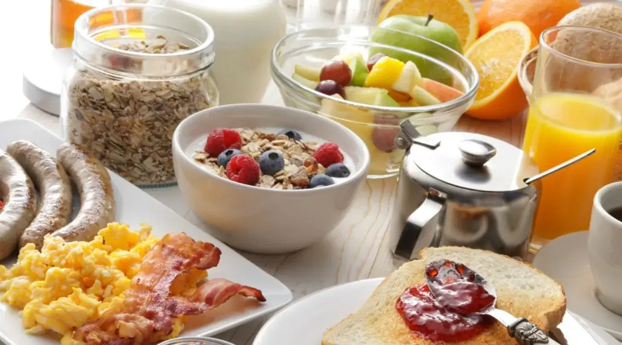 Desayunos para ganar masa muscular: avena, yogur con frutos rojos, huevos, salchichas, tocino, tostadas con mermelada, fruta y zumo.