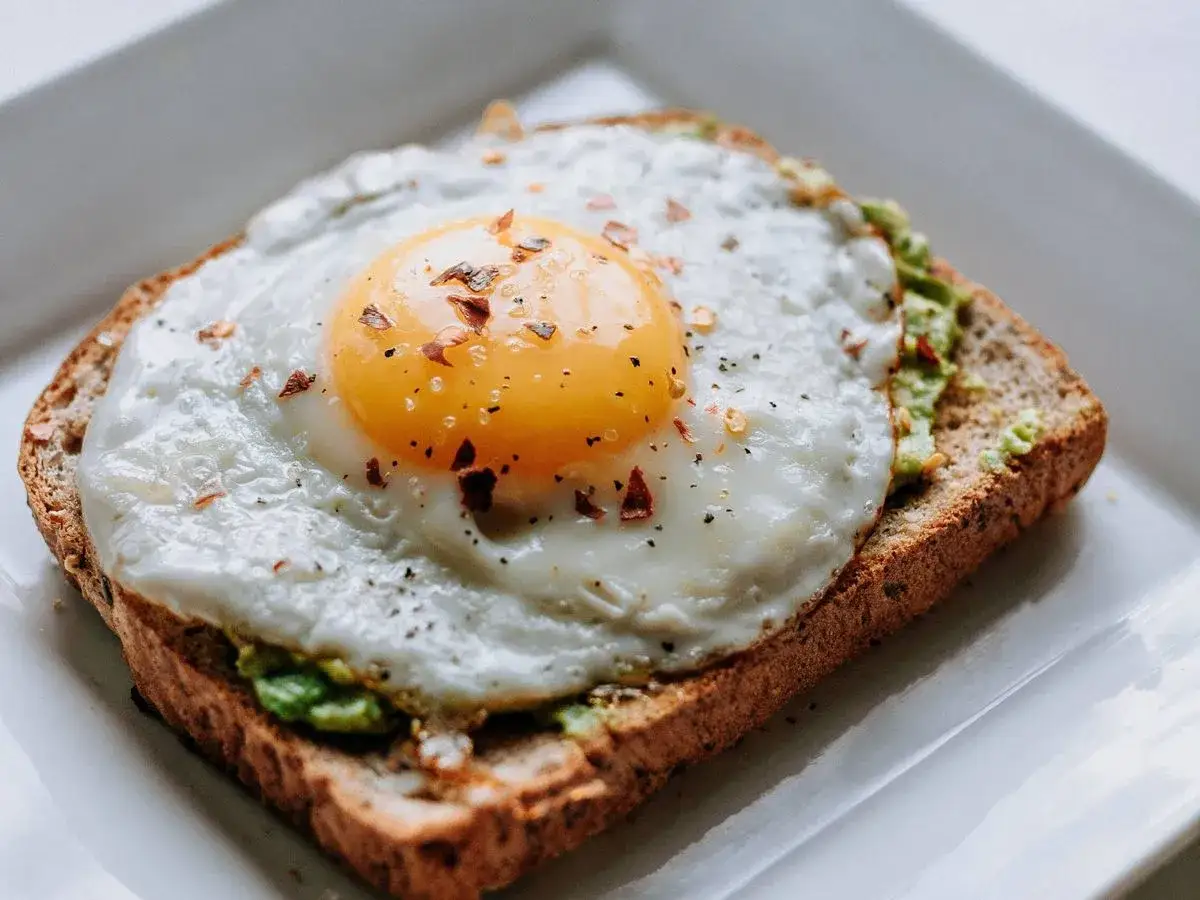 Tostada integral con aguacate y huevo frito, un delicioso desayuno proteico para adelgazar.