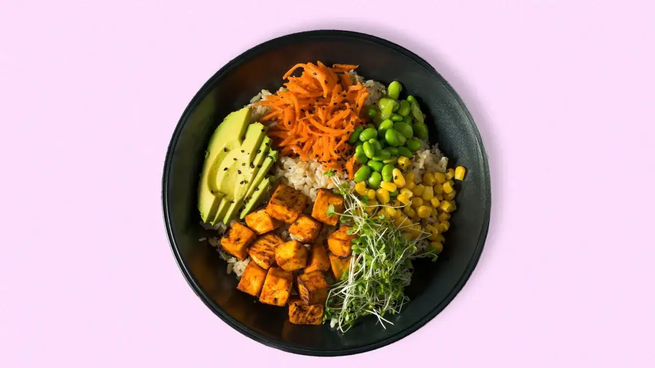 Bowl con arroz integral, aguacate, zanahoria rallada, edamame, maíz y brotes. Una opción deliciosa de alimentos bajos en calorías.