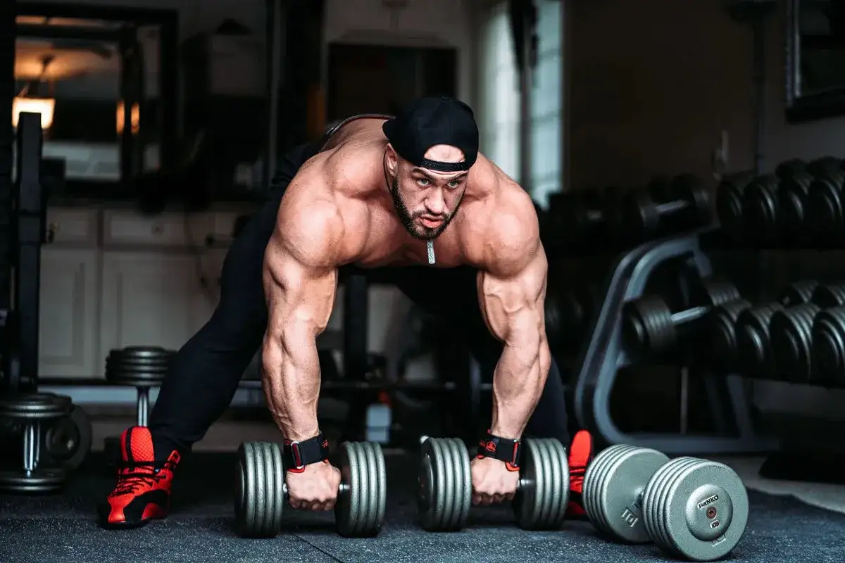 Hombre musculoso levanta pesas en un gimnasio, demostrando cómo ganar masa muscular rápido.