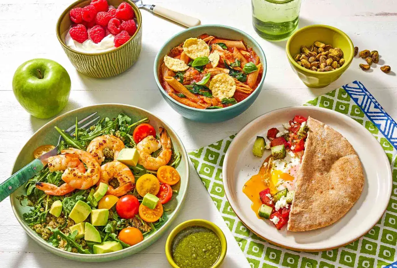 Comida saludable para una dieta rápida para bajar de peso: ensalada de camarones, pasta, huevo con pan pita, yogur con frambuesas y manzana.
