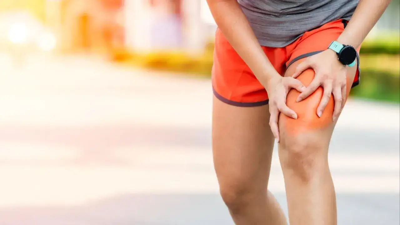 Correr con agujetas puede ser doloroso. Una corredora se agarra la rodilla con una zona enrojecida, indicando molestia.