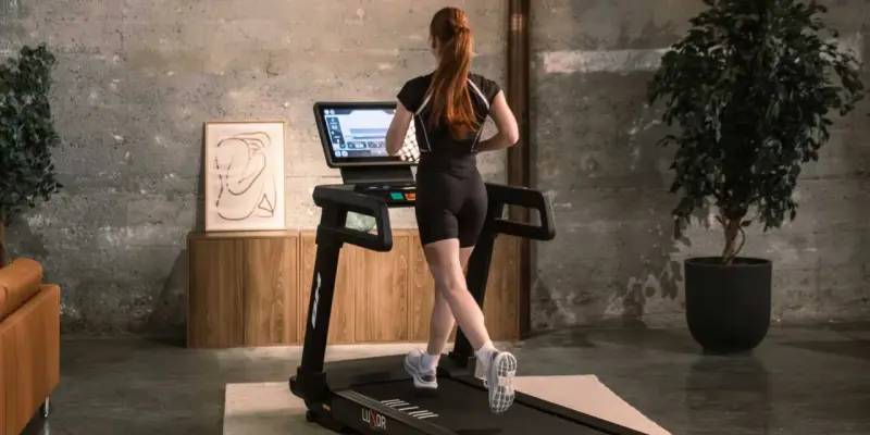 Mujer pelirroja corre en cinta, entrenando en casa con estilo.
